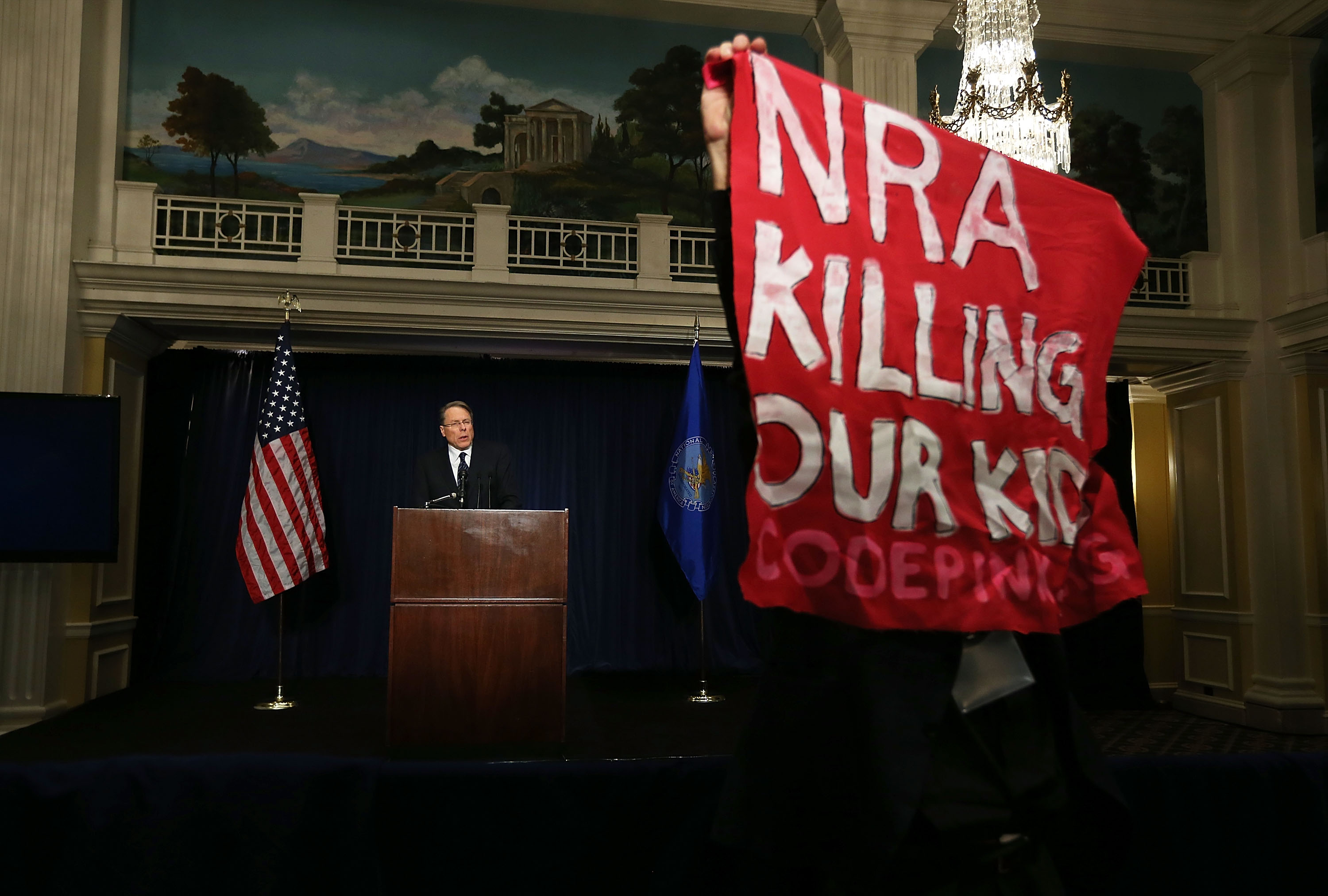 A protester holds up a bannaer as he protests during NRA CEO and Executive Vice President Wayne LaPierre's news conference at the Willard Hotel on December 21, 2012 in Washington, DC. (Photo by Alex Wong/Getty Images) 