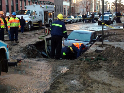 A car is swallowed by a sinkhole after a water main break in Hoboken, NJ on Thursday, March 28, 2013. (credit: Steve Sandberg/1010 WINS)