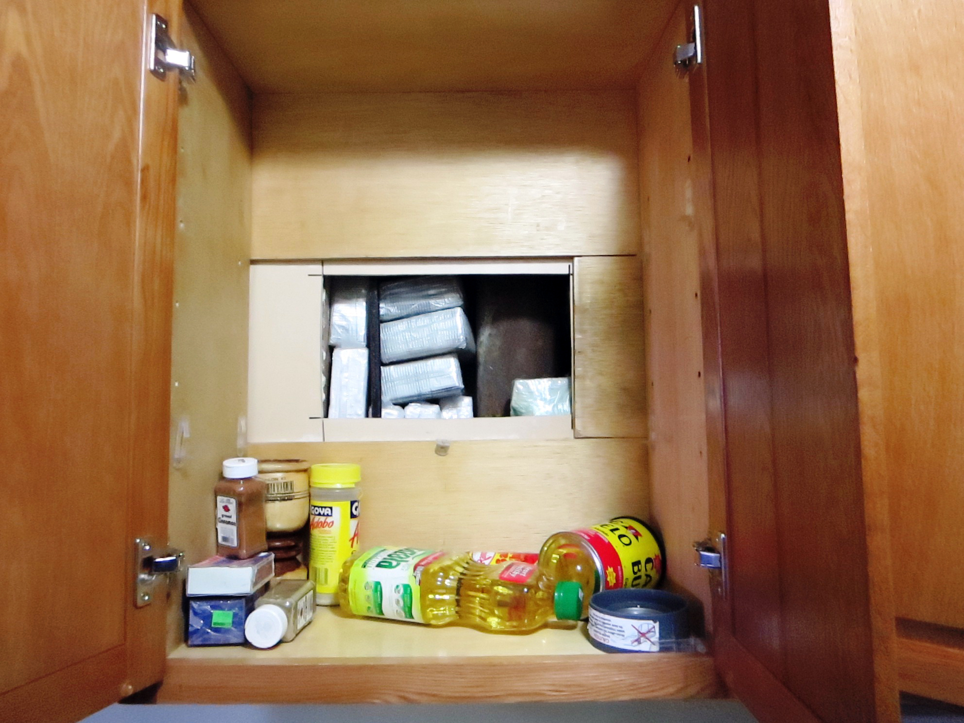 Hidden trap found in kitchen cabinet of Washington Heights apartment used for alleged drug trafficking operation. (credit: Officer of the Special Narcotics Prosecutor)