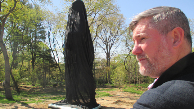 Landscape architect David Kelly stands near sculpture which is now covered up with black mesh fabric (credit: Mona Rivera/1010 WINS)