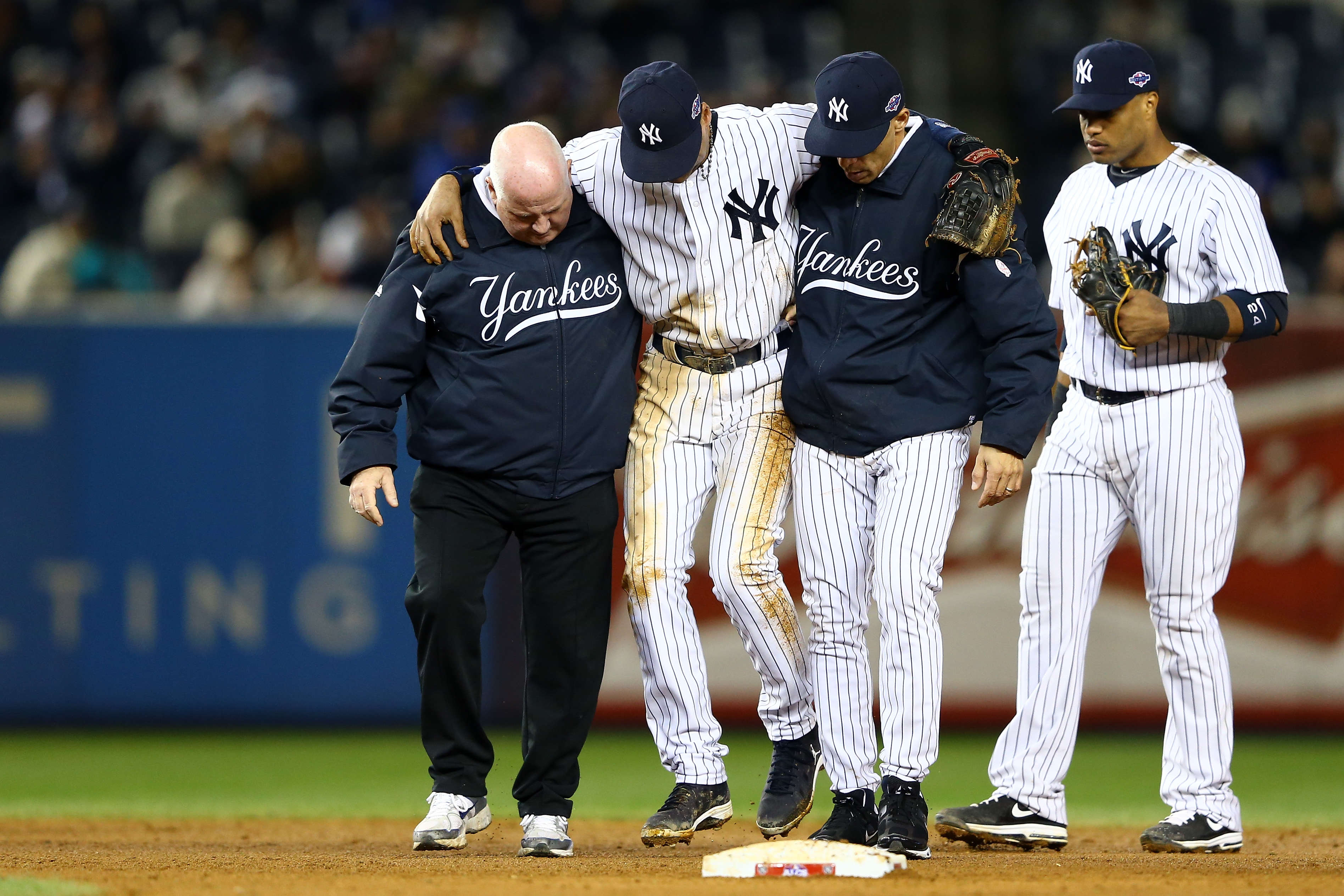 Derek Jeter helped off of the field by trainer Steve Donohue and manager Joe Girardi in the top of the 12th inning against the Detroit Tigers during Game 1 of the 2012 ALCS.  (Photo by Al Bello/Getty Images)