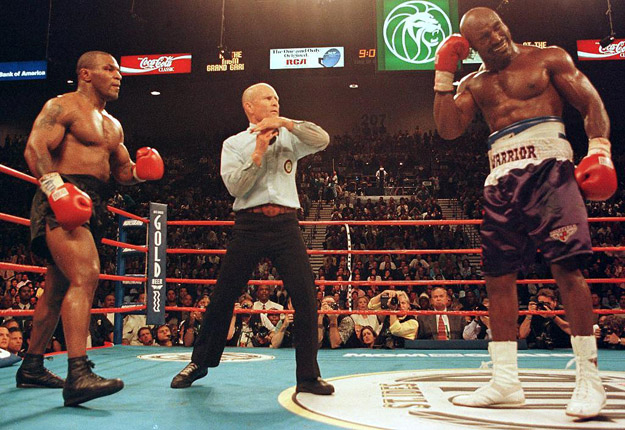 Referee Lane Mills (C) stops the fight in the third round as Evander Holyfield (R) holds his ear as Mike Tyson (L) watches.