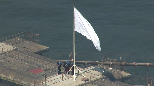 Emergency services officers remove a mysterious white flag from the Brooklyn Bridge on July 22, 2014. (credit: CBS 2)